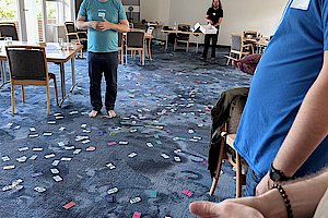 Pluscamp 2023 - agile coach Thorsten in masses of cards from the agile card game Lucky Salmon on the carpeted floor
