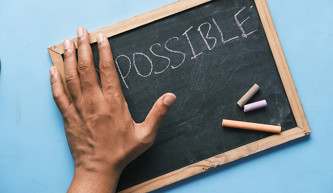 Possible versus Impossible Hand auf Kreidetafel mit Text: Possible