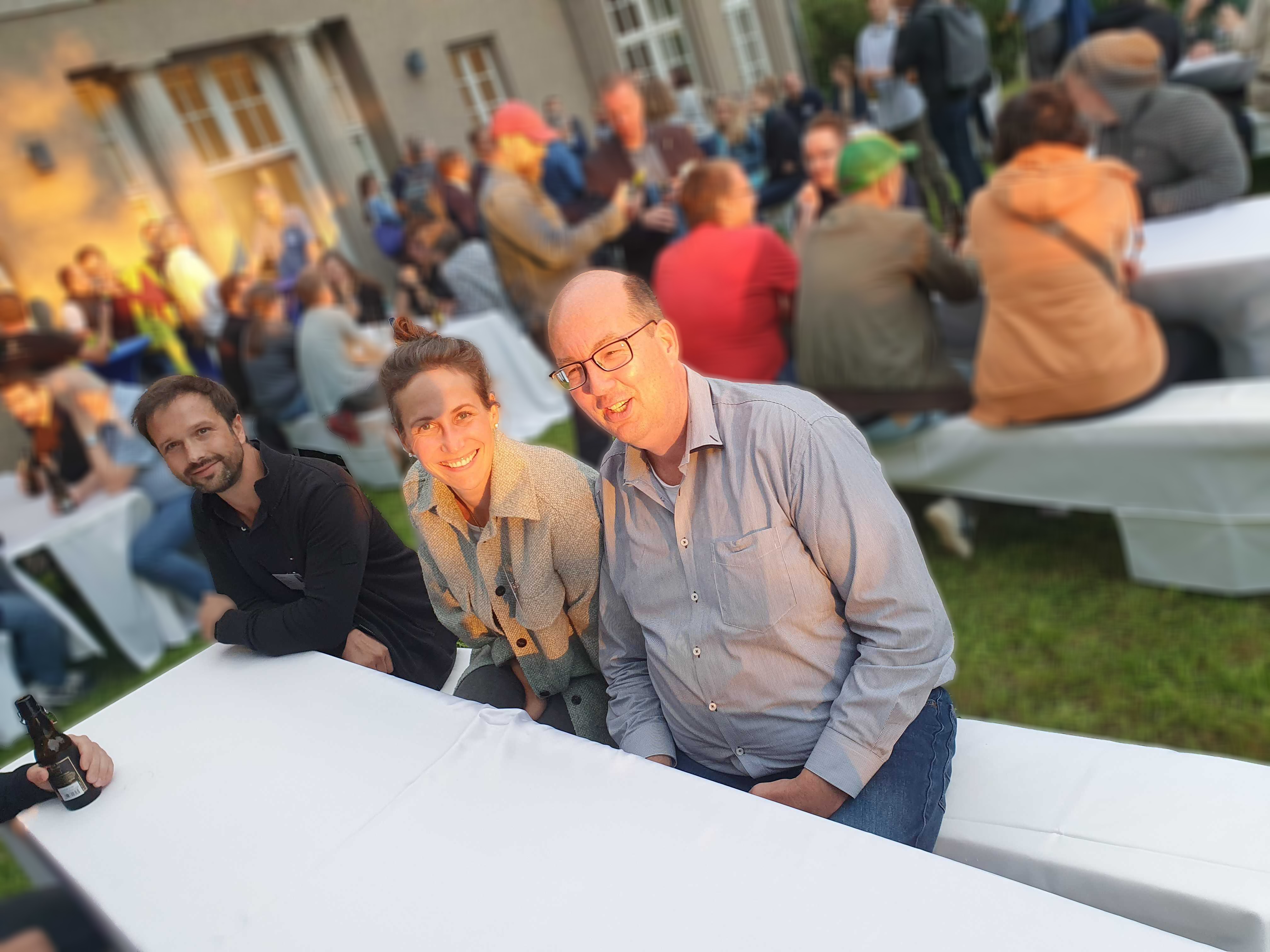 Image of the garden of the evening event at the TYPO3 University Days with participants seetinat white covered tabels